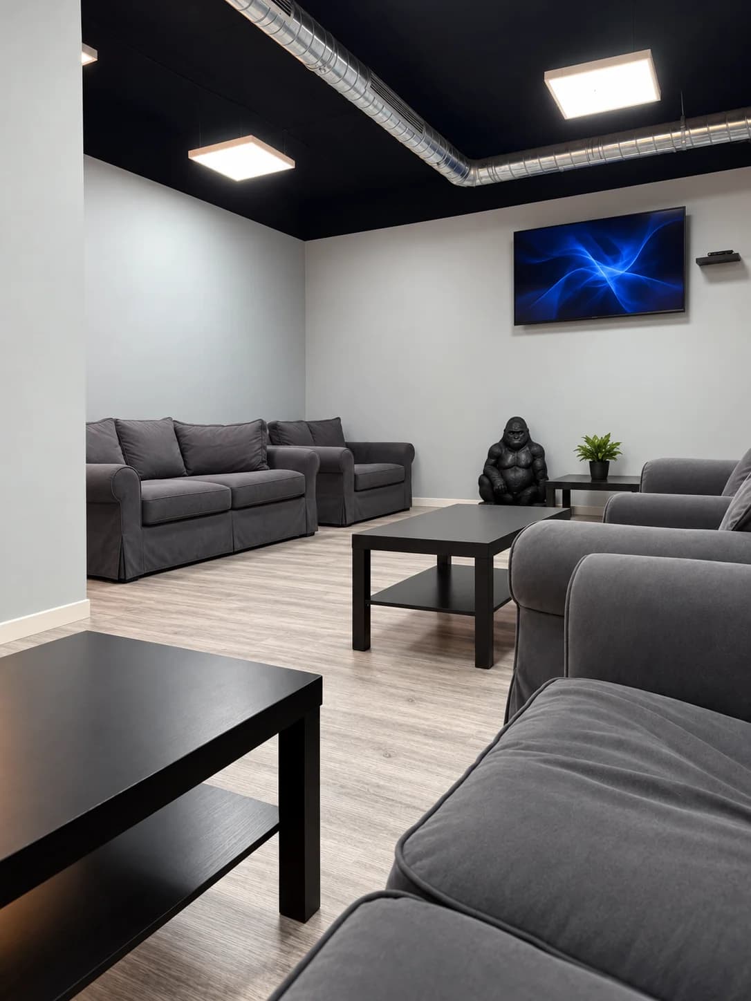 Weed Club Malasaña lounge in Madrid with grey sofas, black tables and a television