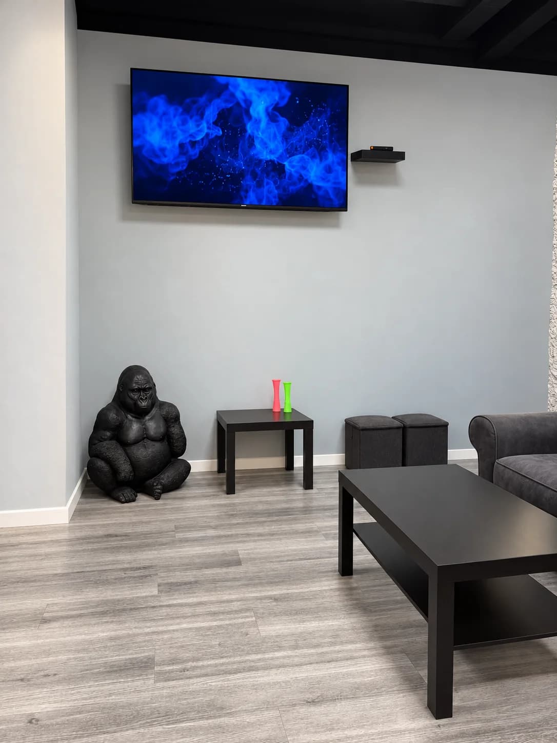 Television area at Weed Club Malasaña with black tables and a gorilla figure